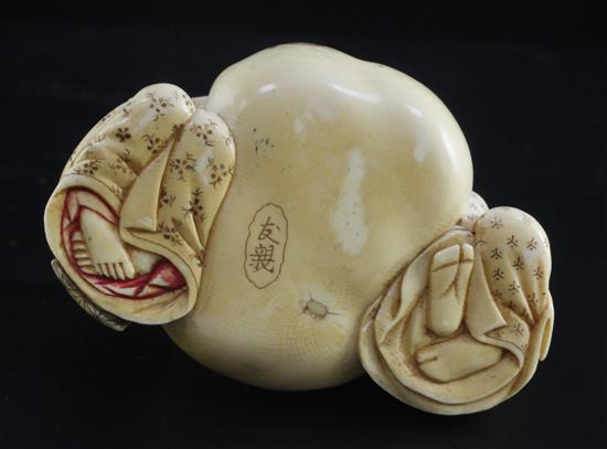 A Japanese ivory okimono of a man and woman holding the cords of a tied sack between them, Meiji period, width 7.3cm